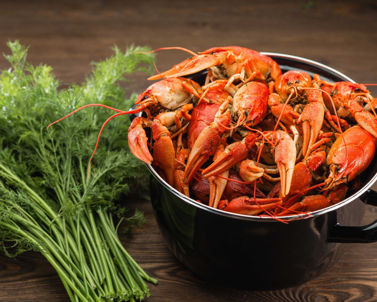 Boiled crayfish in a pan on the table with dill
