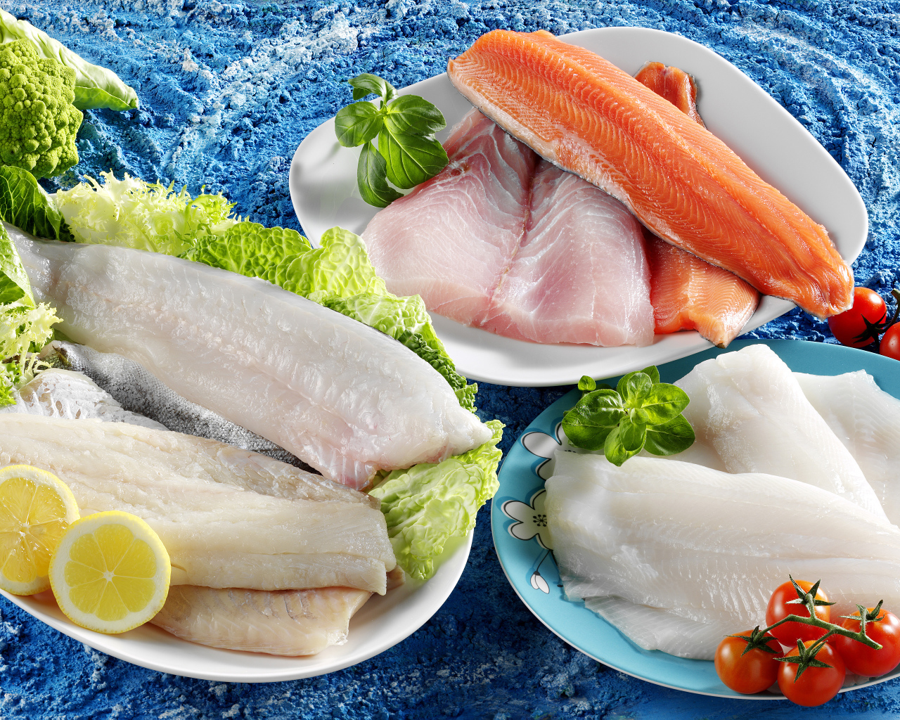 Филе рыбы на тарелках с помидорами и листьями салата