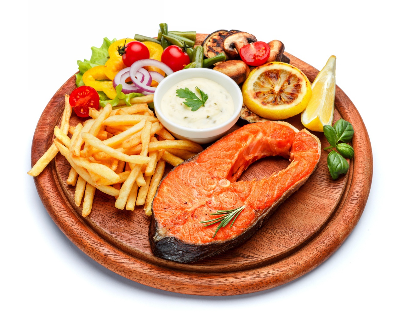 Fish on a board with french fries, vegetables and sauce