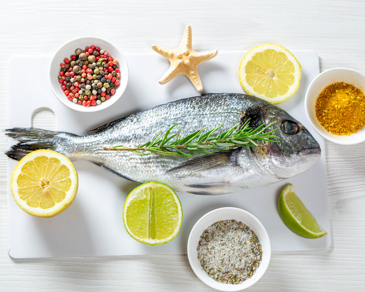 Свежая рыба на доске с солью, перцем, куркумой и лимоном