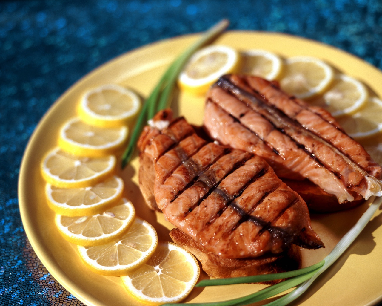 Зажаренная красная рыба с кусочками лимона и зеленым луком