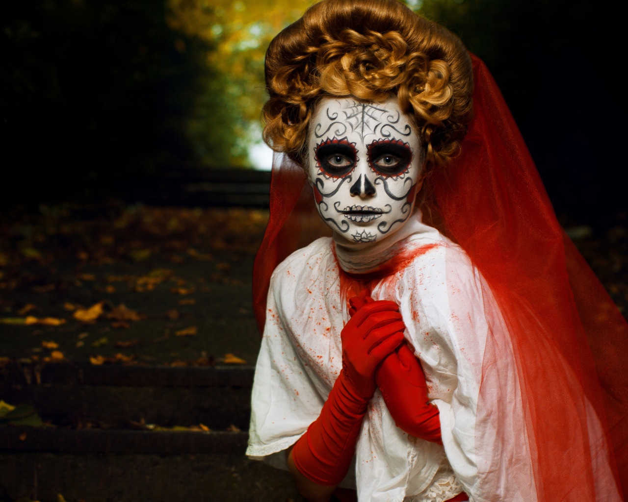 Девушка с маской на лице и красной фатой на праздник Хэллоуин 