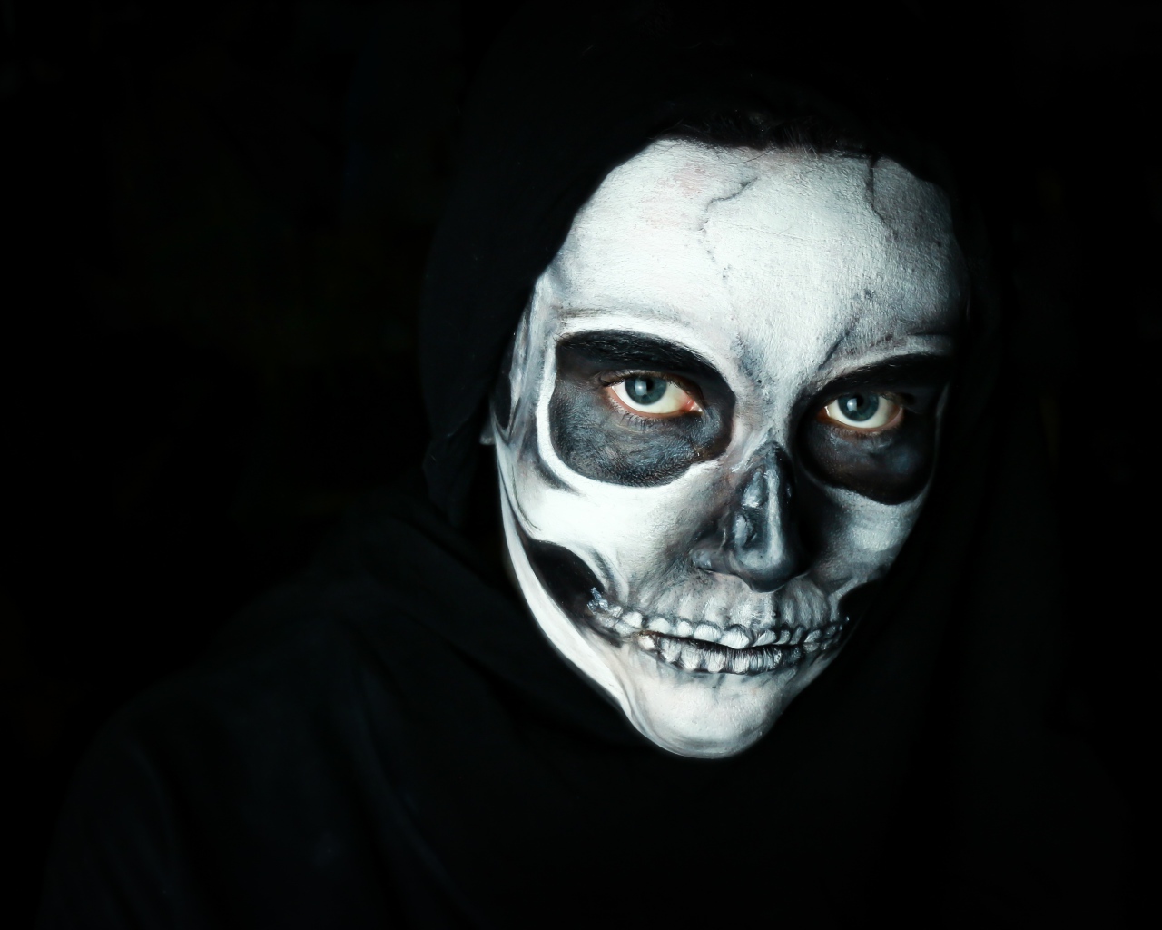 Девушка с маской с грима на лице на черном фоне