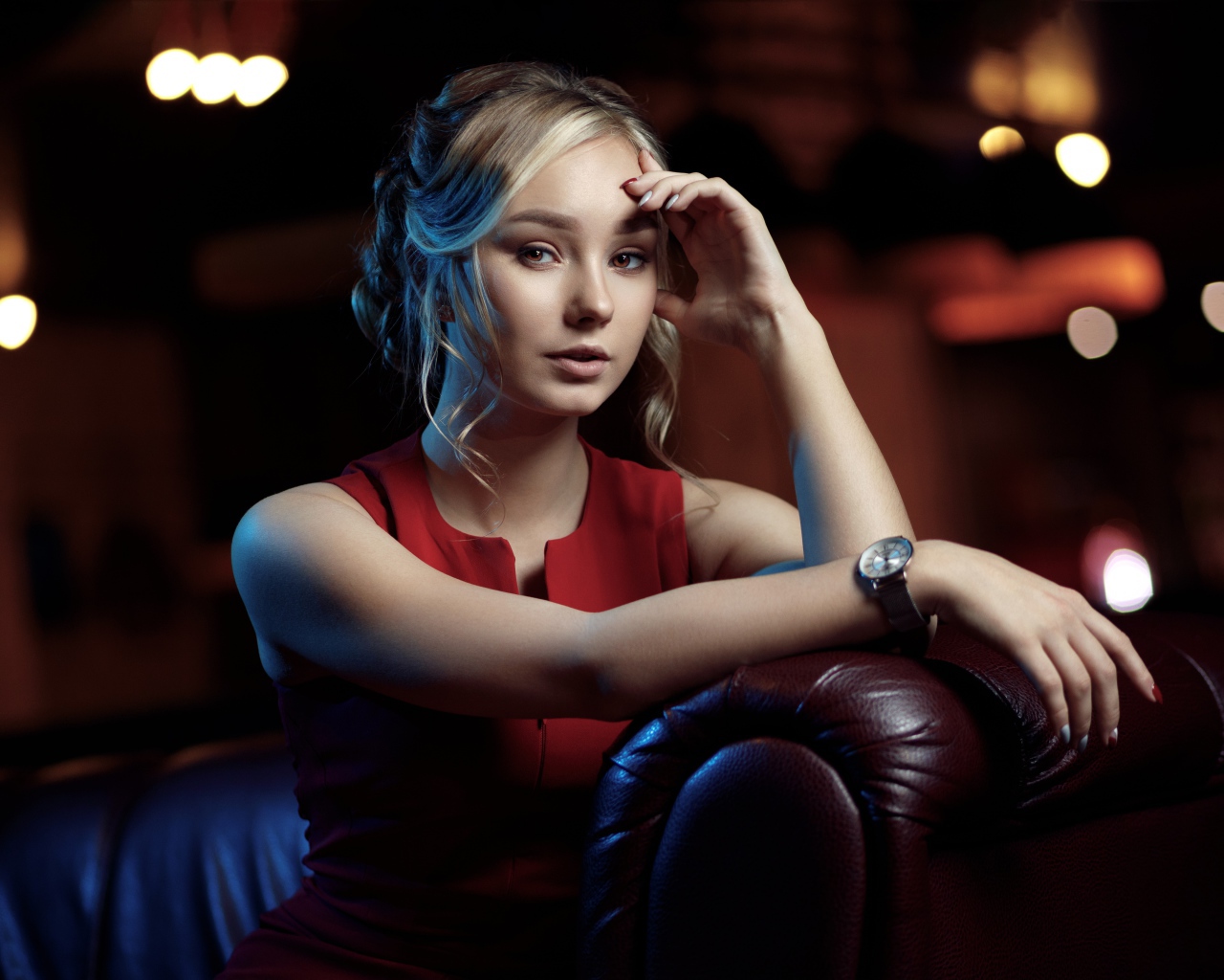 Красивая девушка с часами на руке сидит в кресле