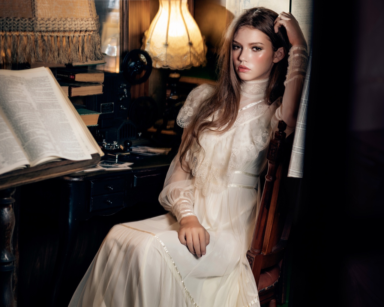 Девушка в красивом белом платье сидит на стуле у стола