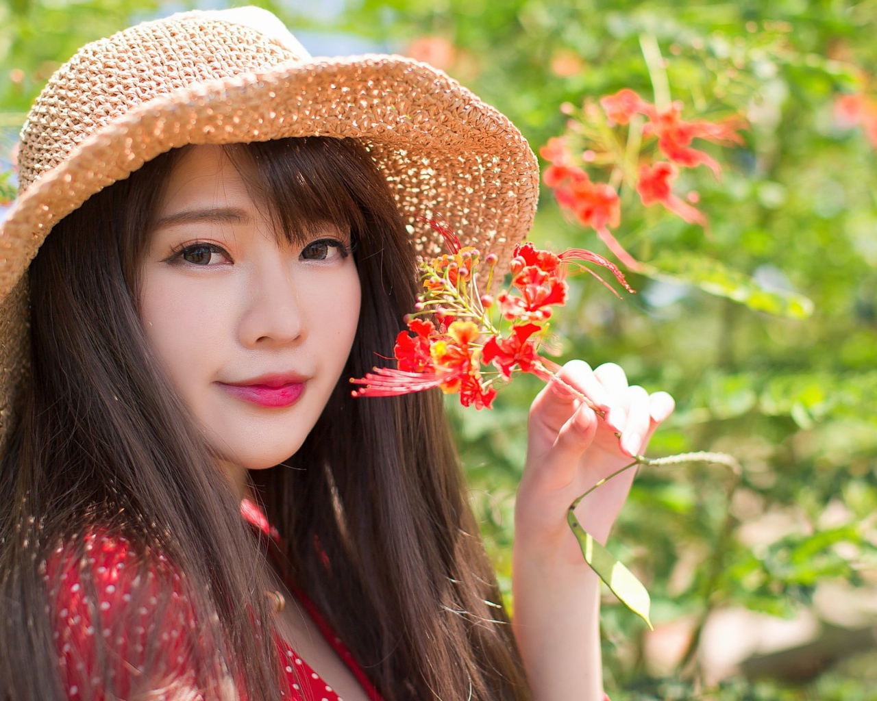 Девушка азиатка в шляпе с красным цветком