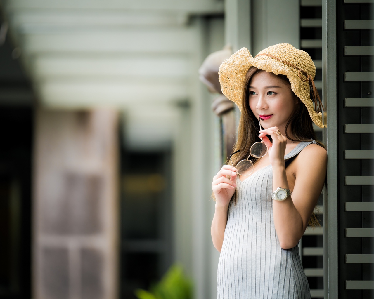 Девушка азиатка в шляпке с очками в руках 