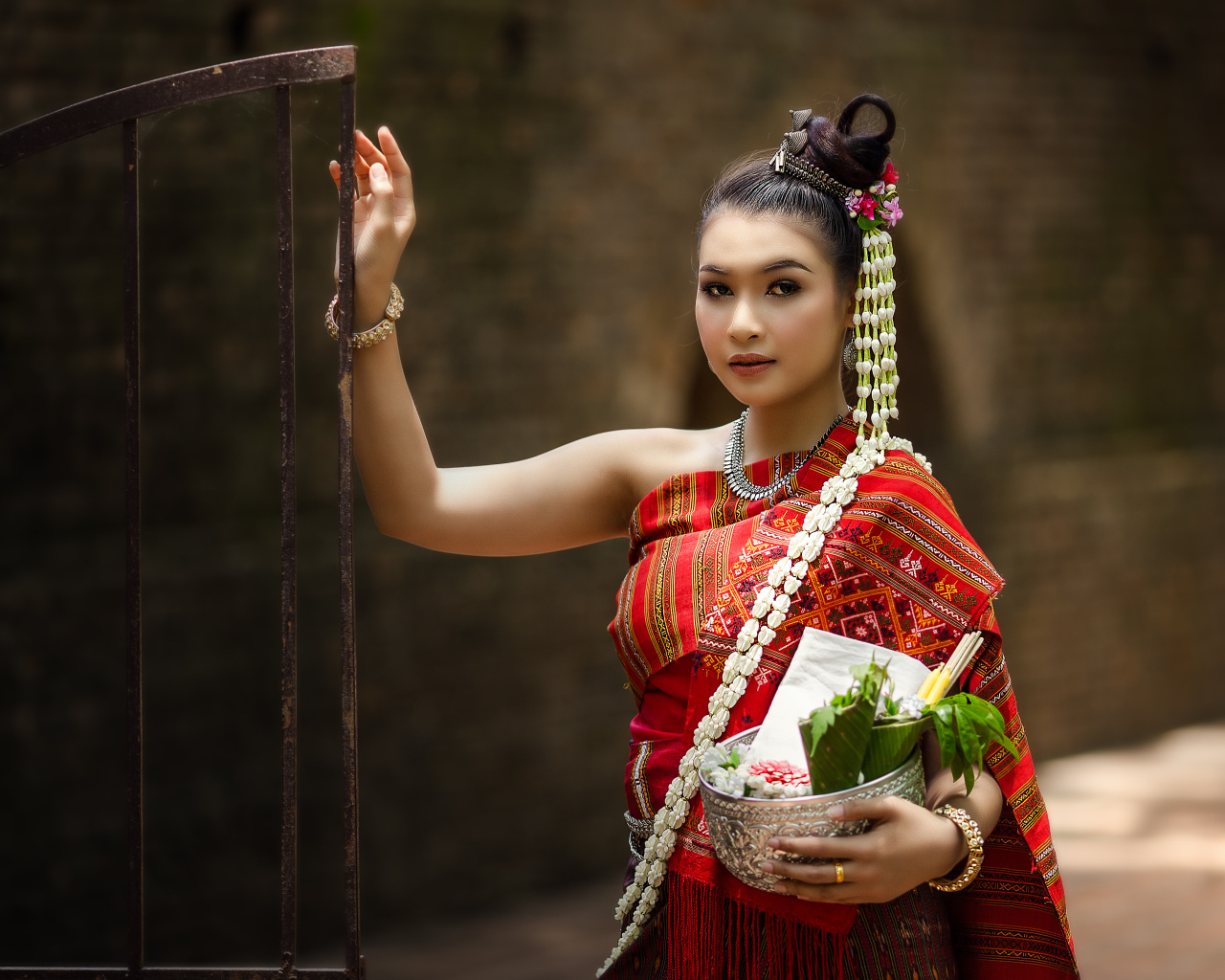 Девушка азиатка в костюме стоит у железных ворот