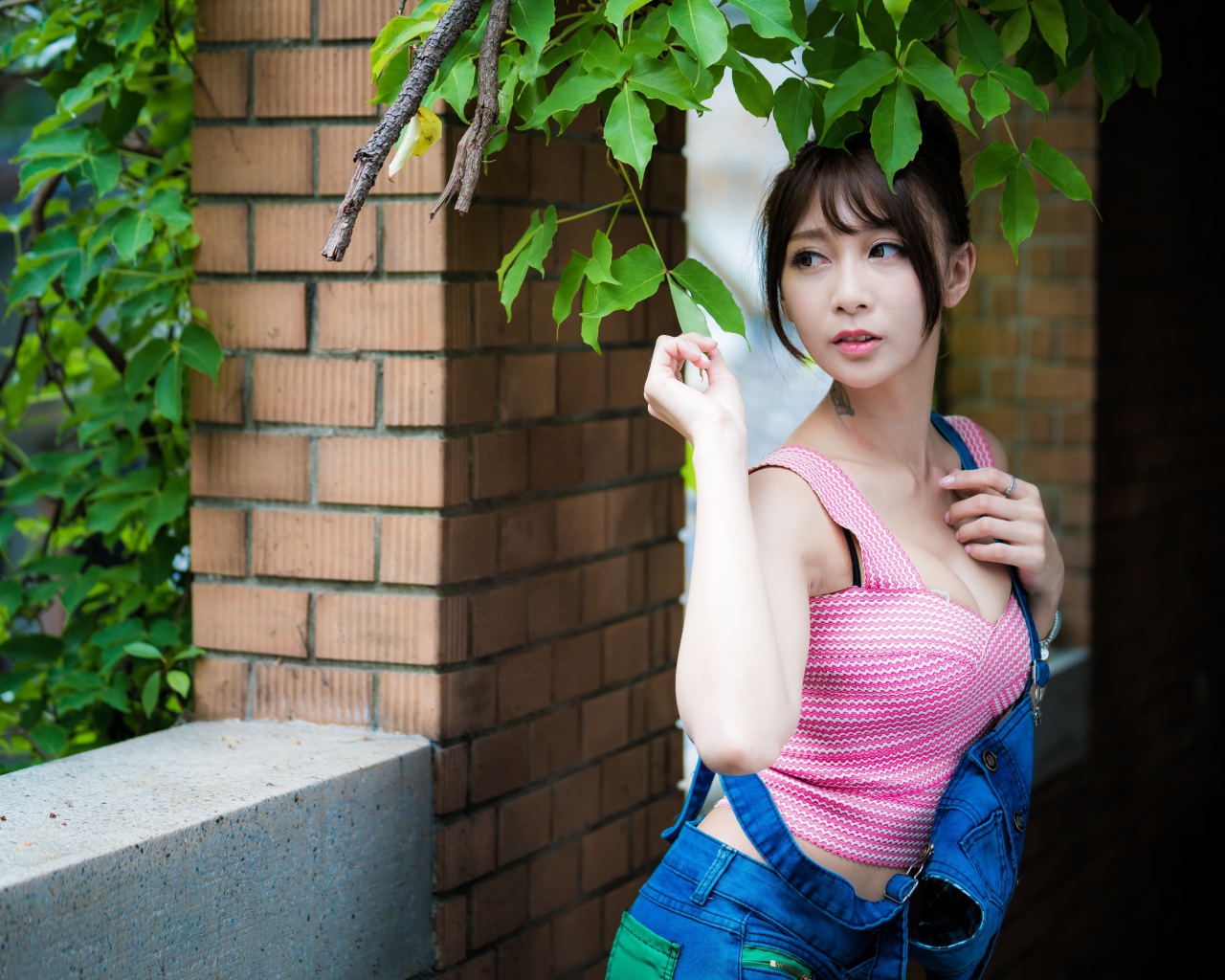 Молодая девушка азиатка у стены с зелеными листьями