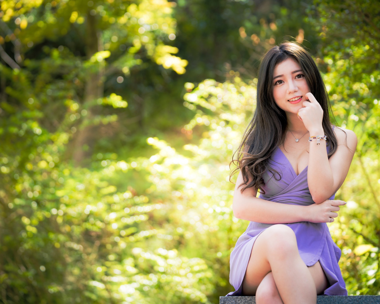 Молодая девушка азиатка сидит на лавке в парке