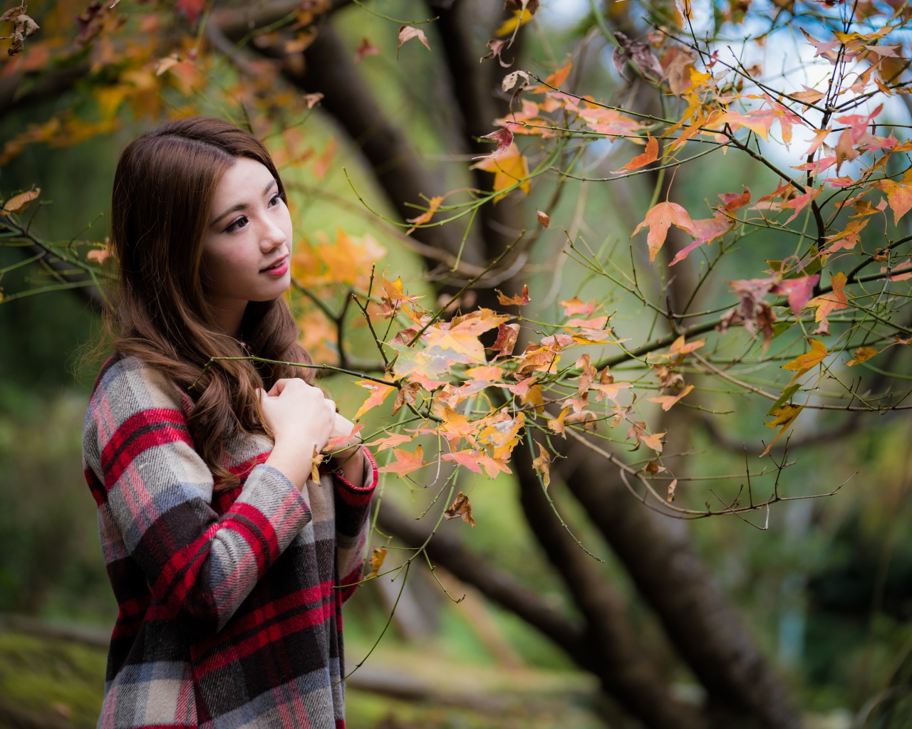 Красивая азиатка стоит у дерева