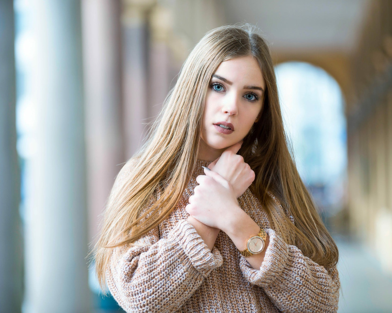Красивая голубоглазая блондинка в теплом свитере с часами на руке