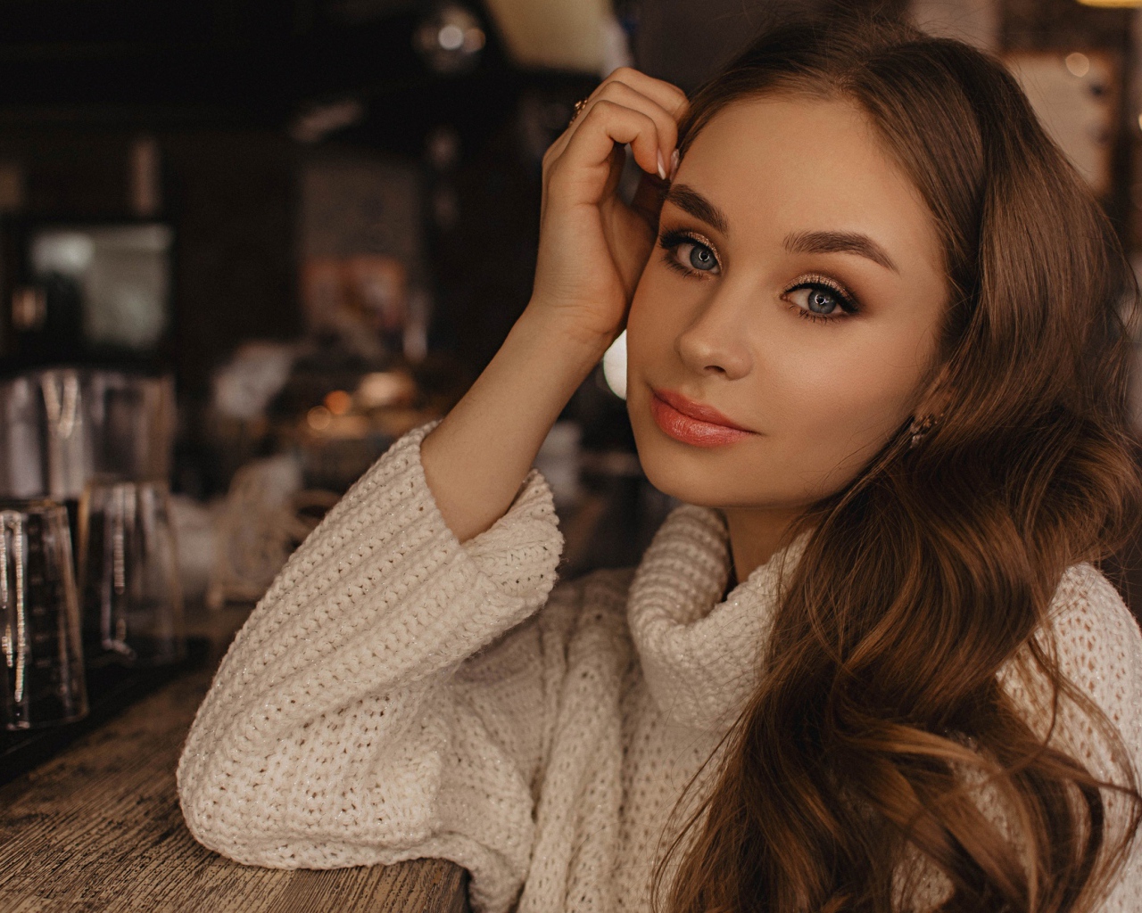 Красивая голубоглазая девушка в белом свитере в кафе