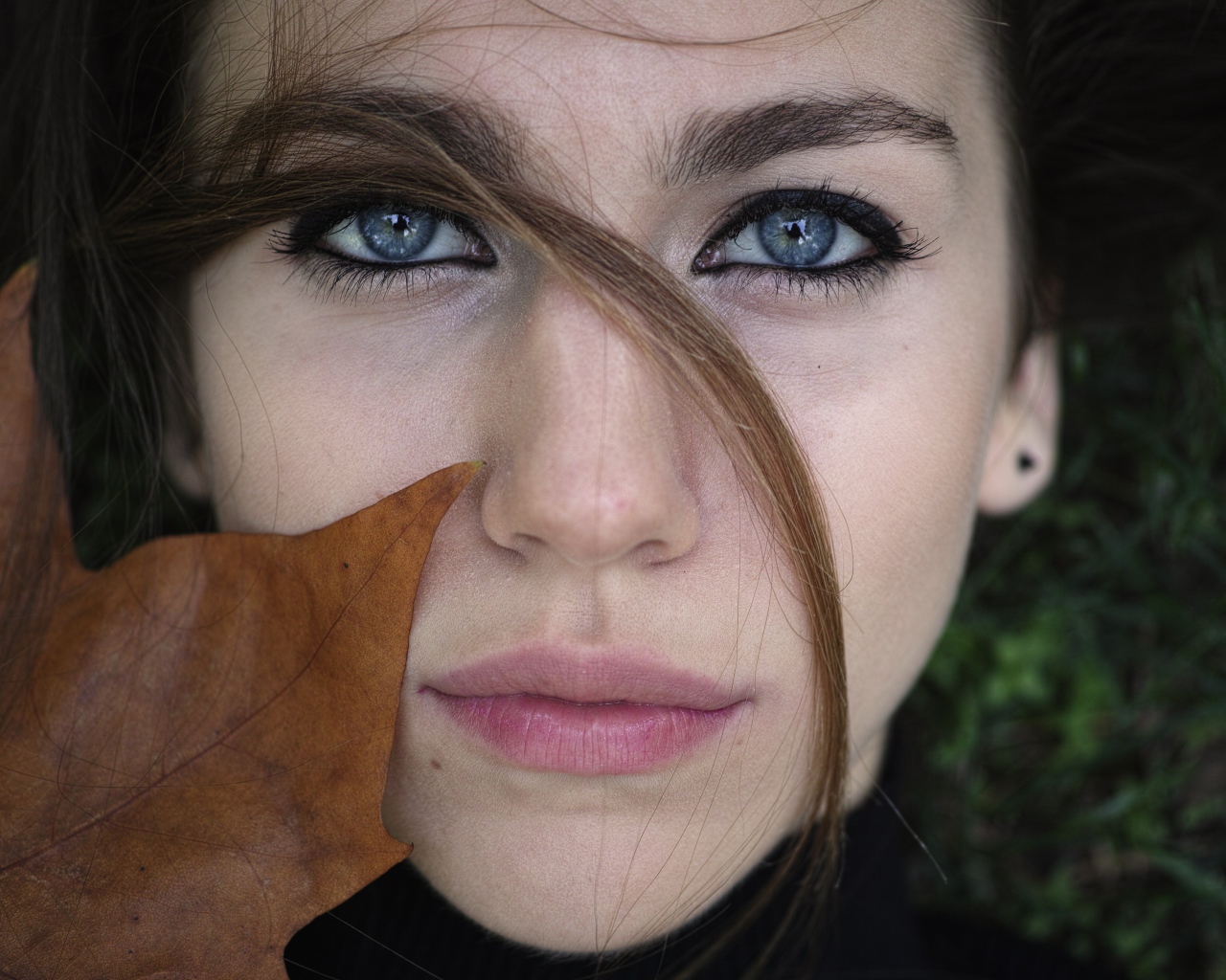 Красивая голубоглазая девушка с желтым листом у лица