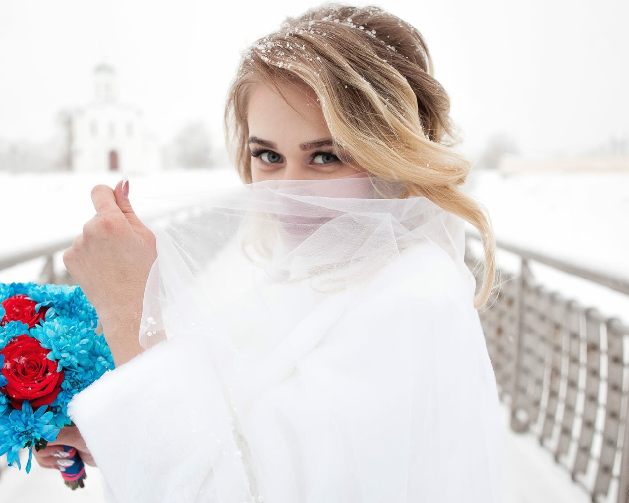 Красивая невеста с букетом в руках закрывает лицо фатой