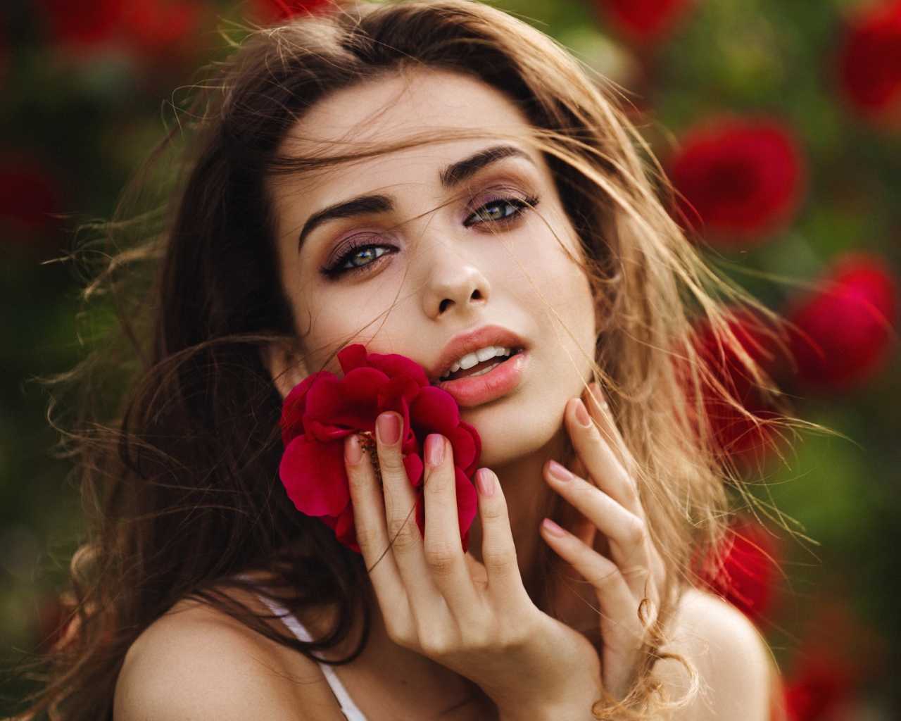 Красивая девушка шатенка с цветком у лица