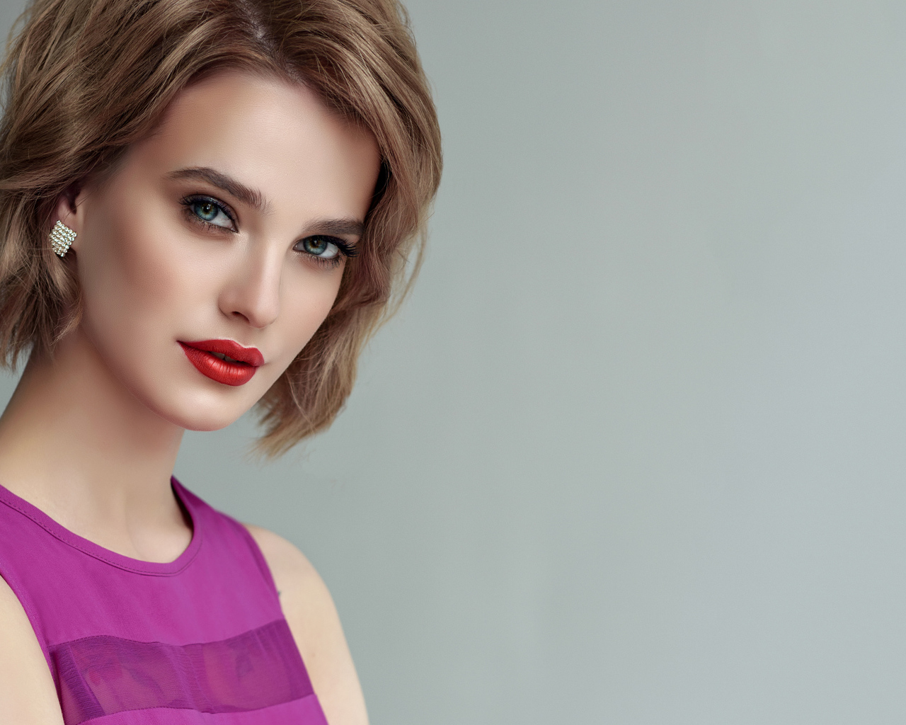 Красивая девушка шатенка с короткой стрижкой на сером фоне