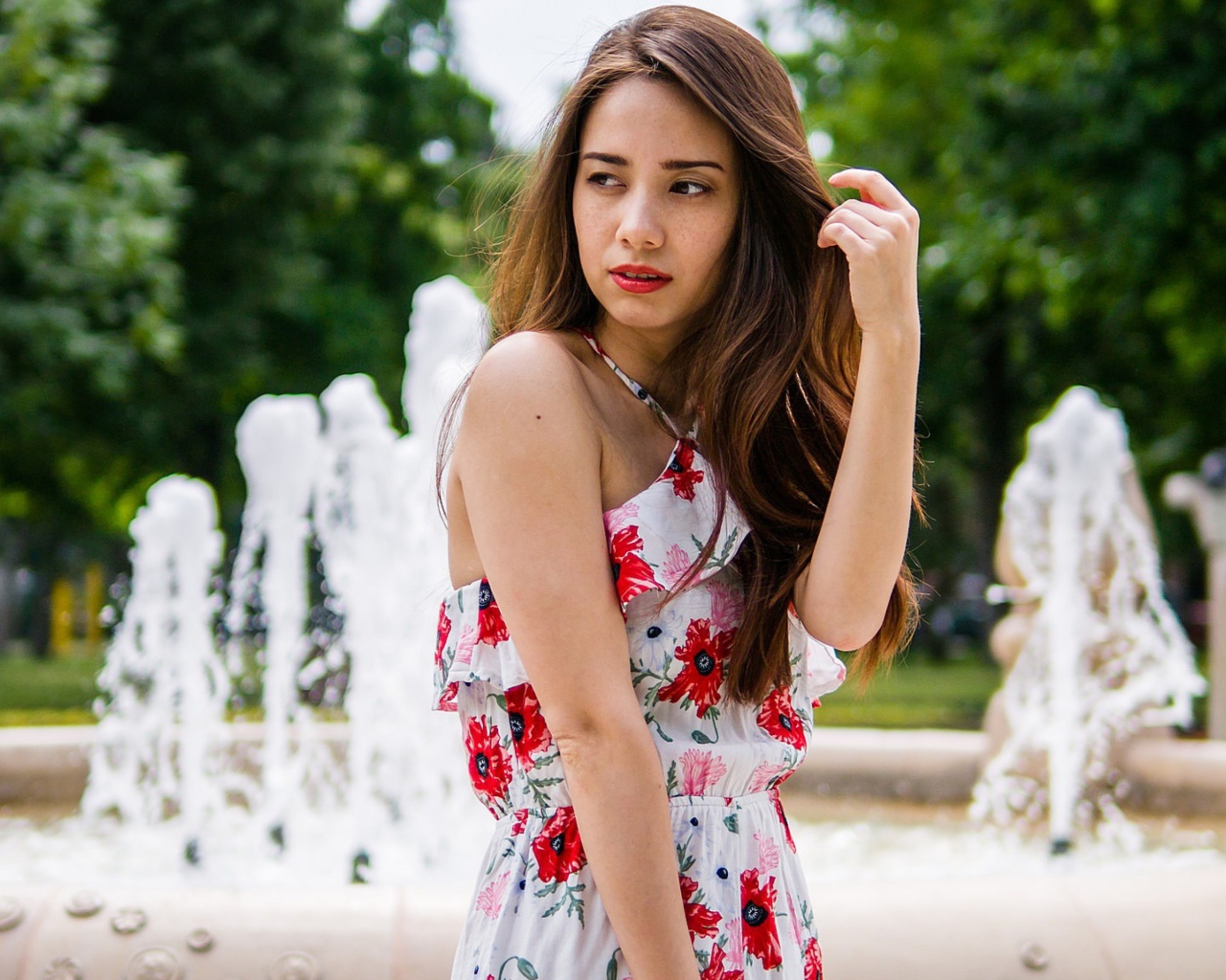 Красивая шатенка в цветастом платье у фонтана летом