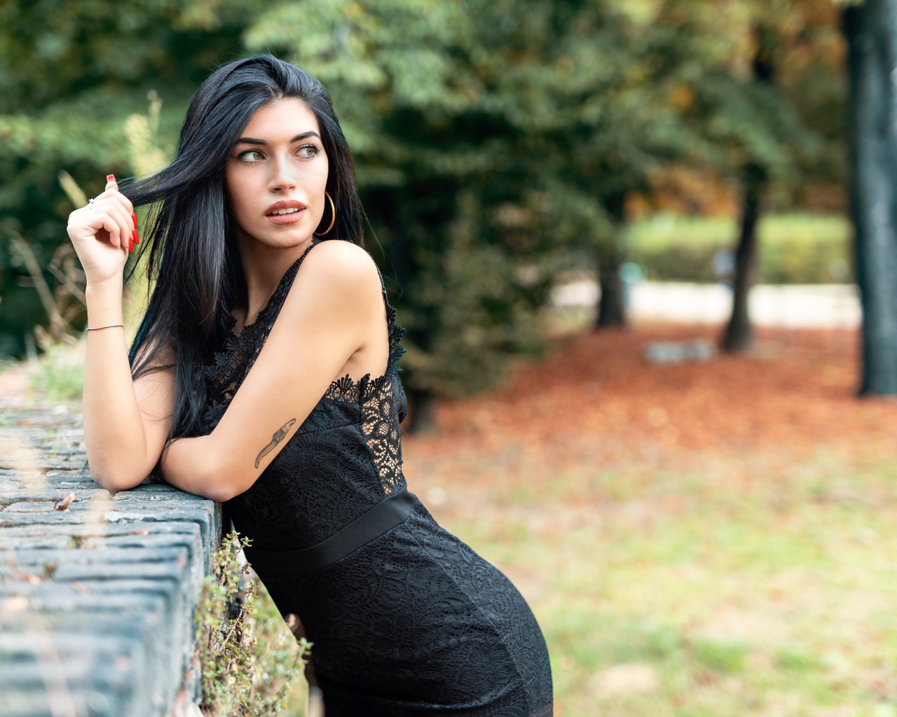 Красивая брюнетка в черном платье в парке