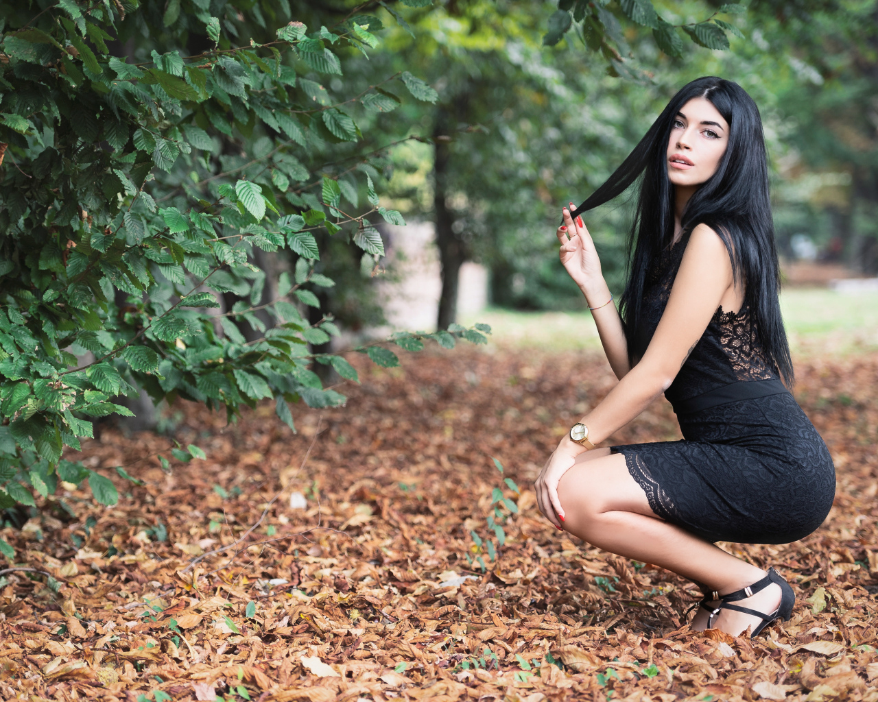 Красивая брюнетка в черном платье в парке осенью 