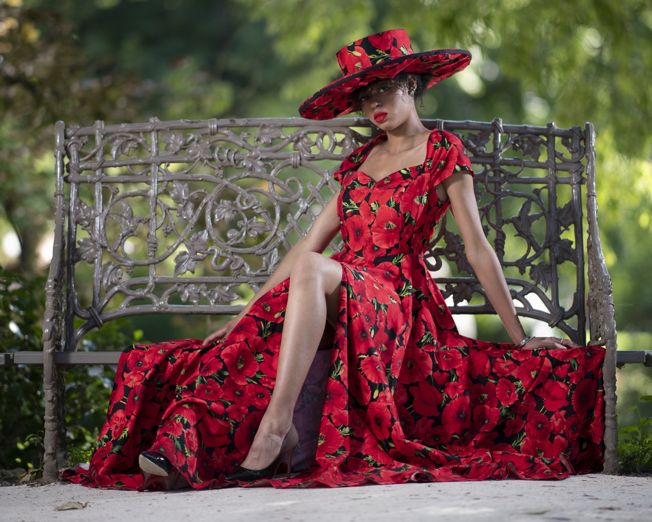 Красивая темнокожая девушка в красном платье сидит на лавке