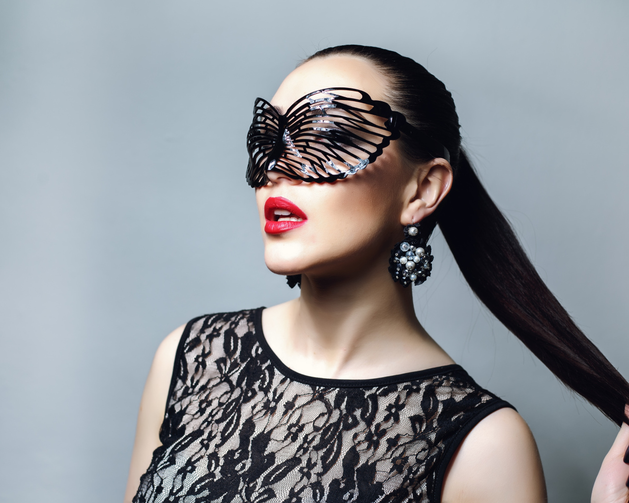 Красивая модная девушка в черной маске на сером фоне