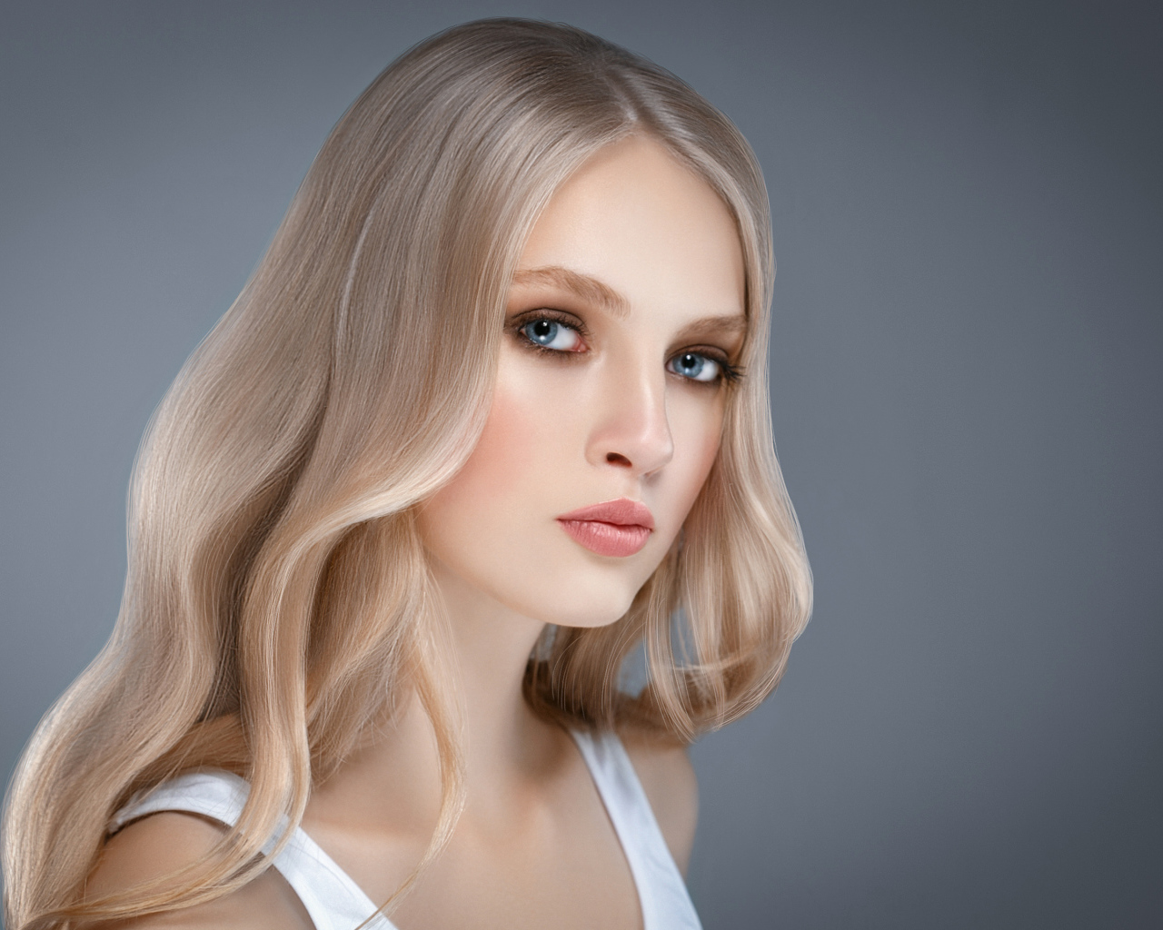 Красивая нежная голубоглазая блондинка на сером фоне