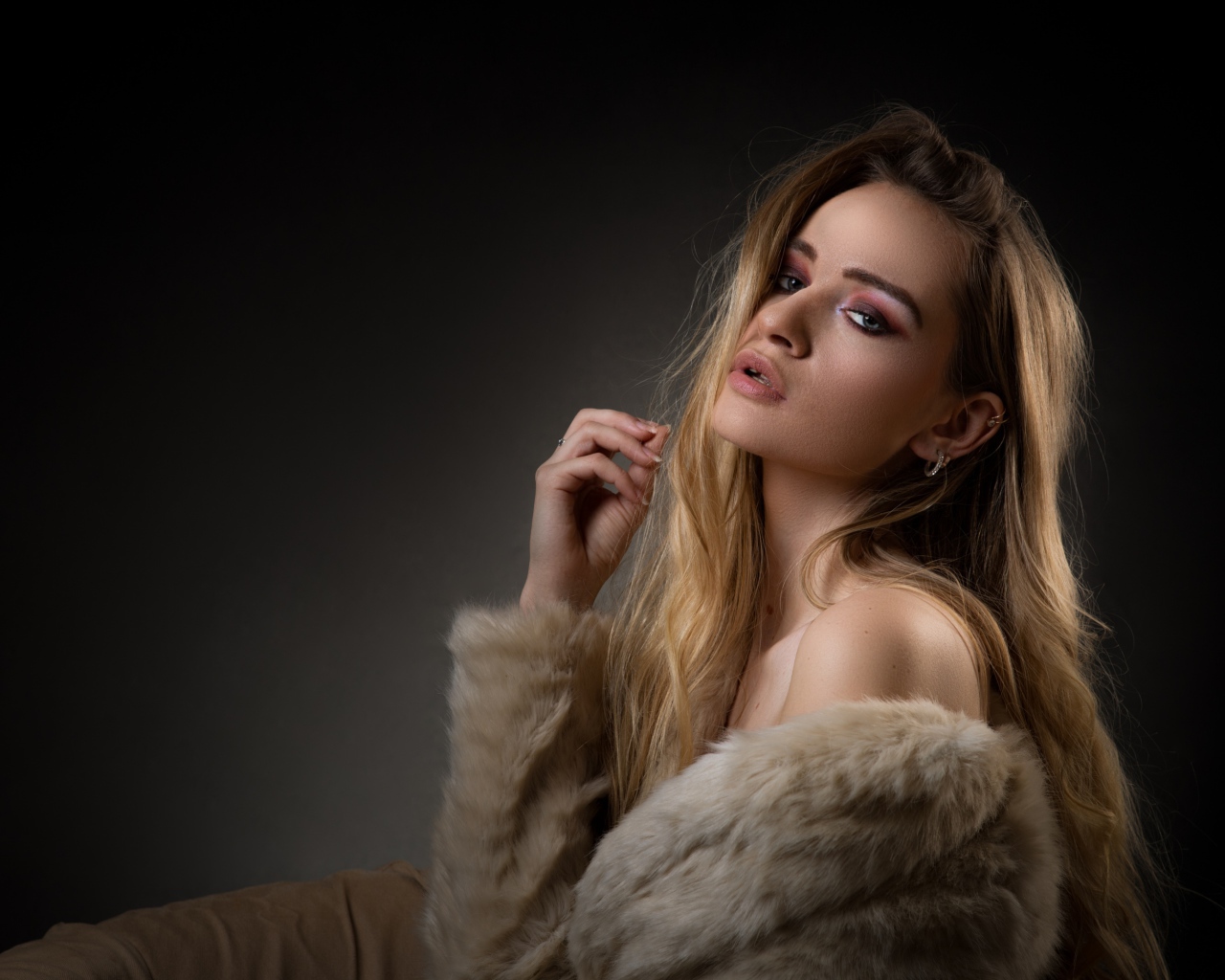 Beautiful girl in a fur coat on a gray background