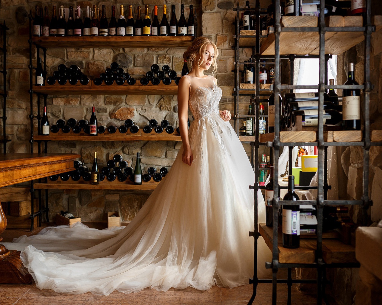 Красивая девушка в пышном свадебном платье в винном погребе