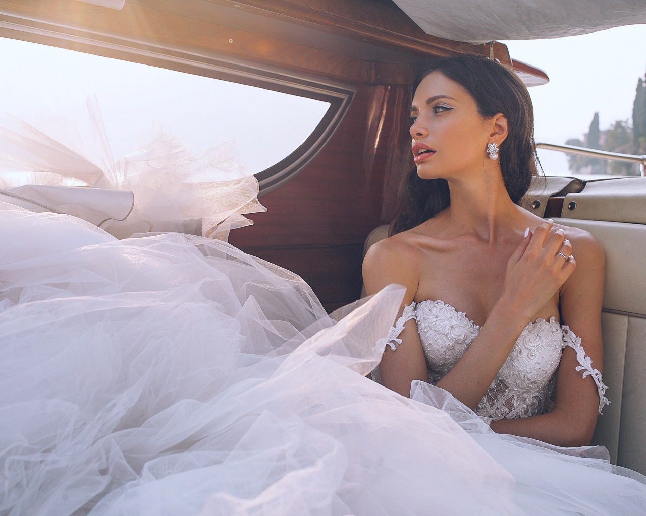 Красивая девушка в белом свадебном платье в машине