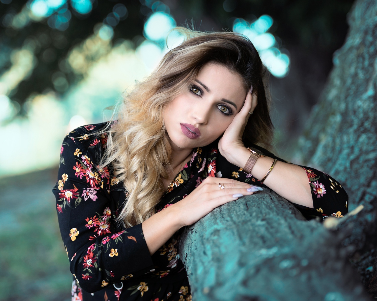 Красивая девушка в цветастом платье у дерева