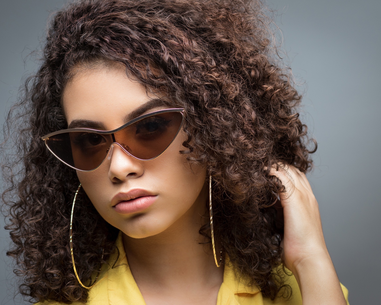 Красивая девушка в солнечных очках на сером фоне