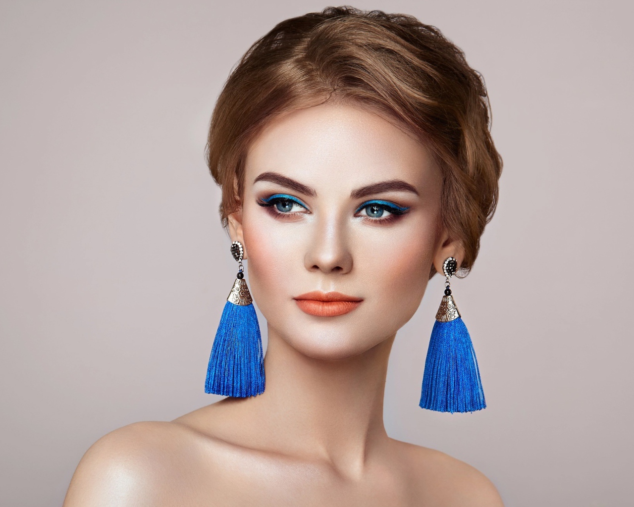 Красивая девушка с синими сережками на сером фоне