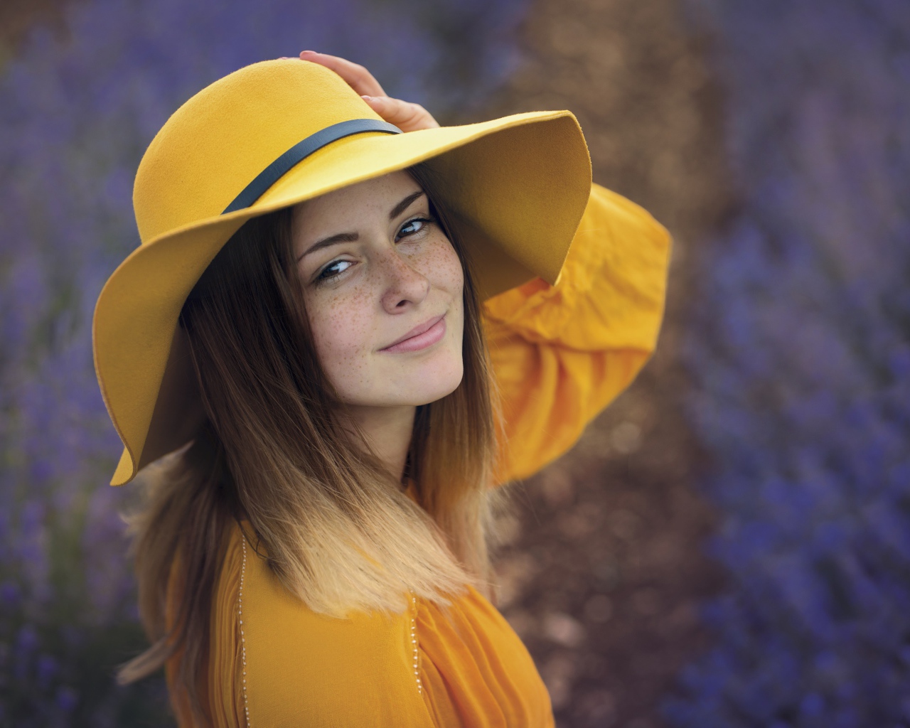 Красивая девушка с веснушками на лице в желтой шляпе