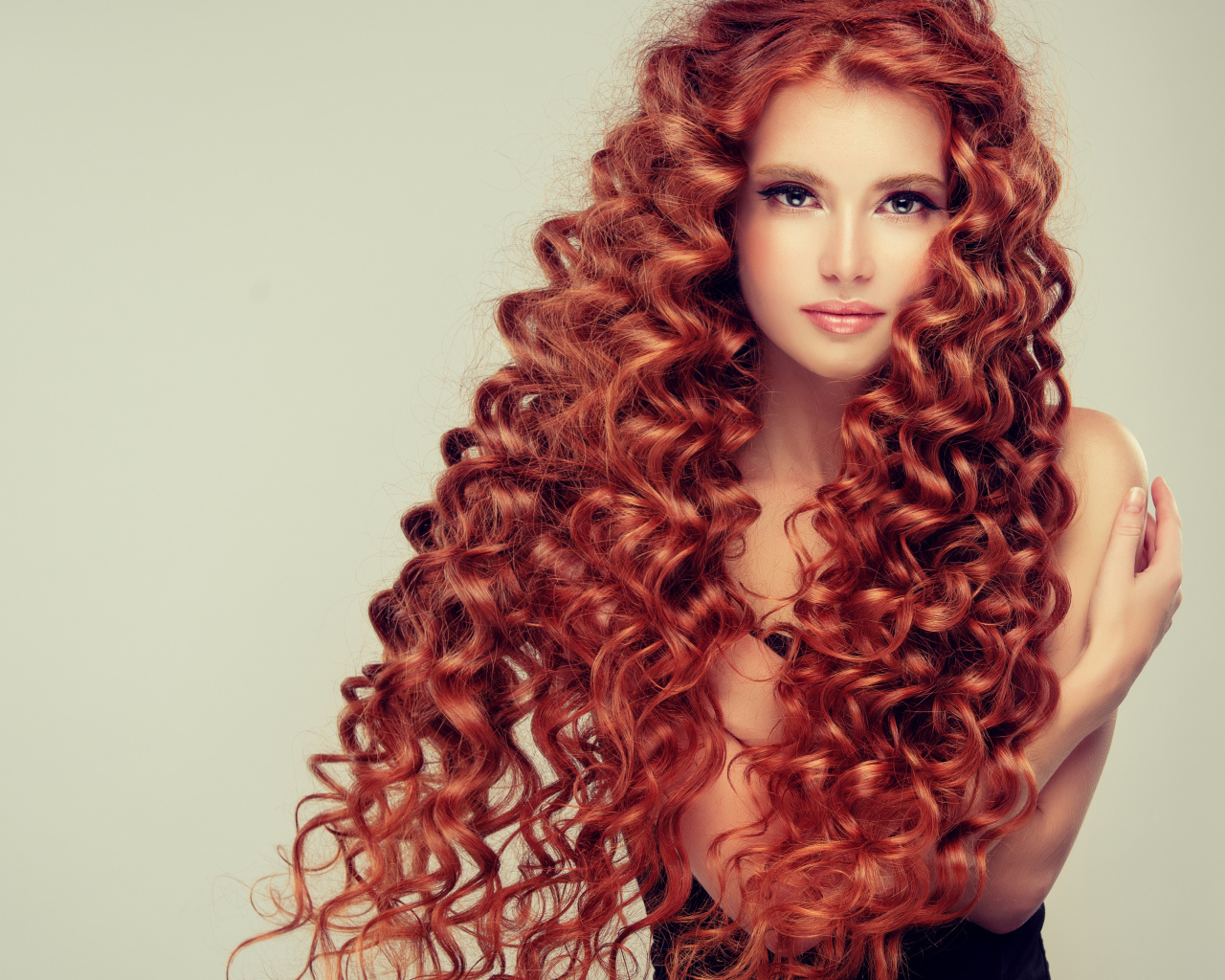 Красивая девушка с длинными рыжими волосами на сером фоне