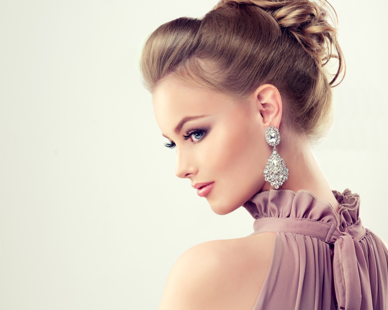 Красивая девушка с макияжем и прической на сером фоне