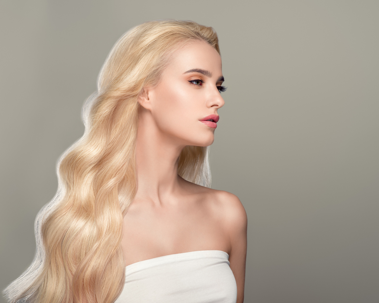 Красивая длинноволосая девушка блондинка на сером фоне