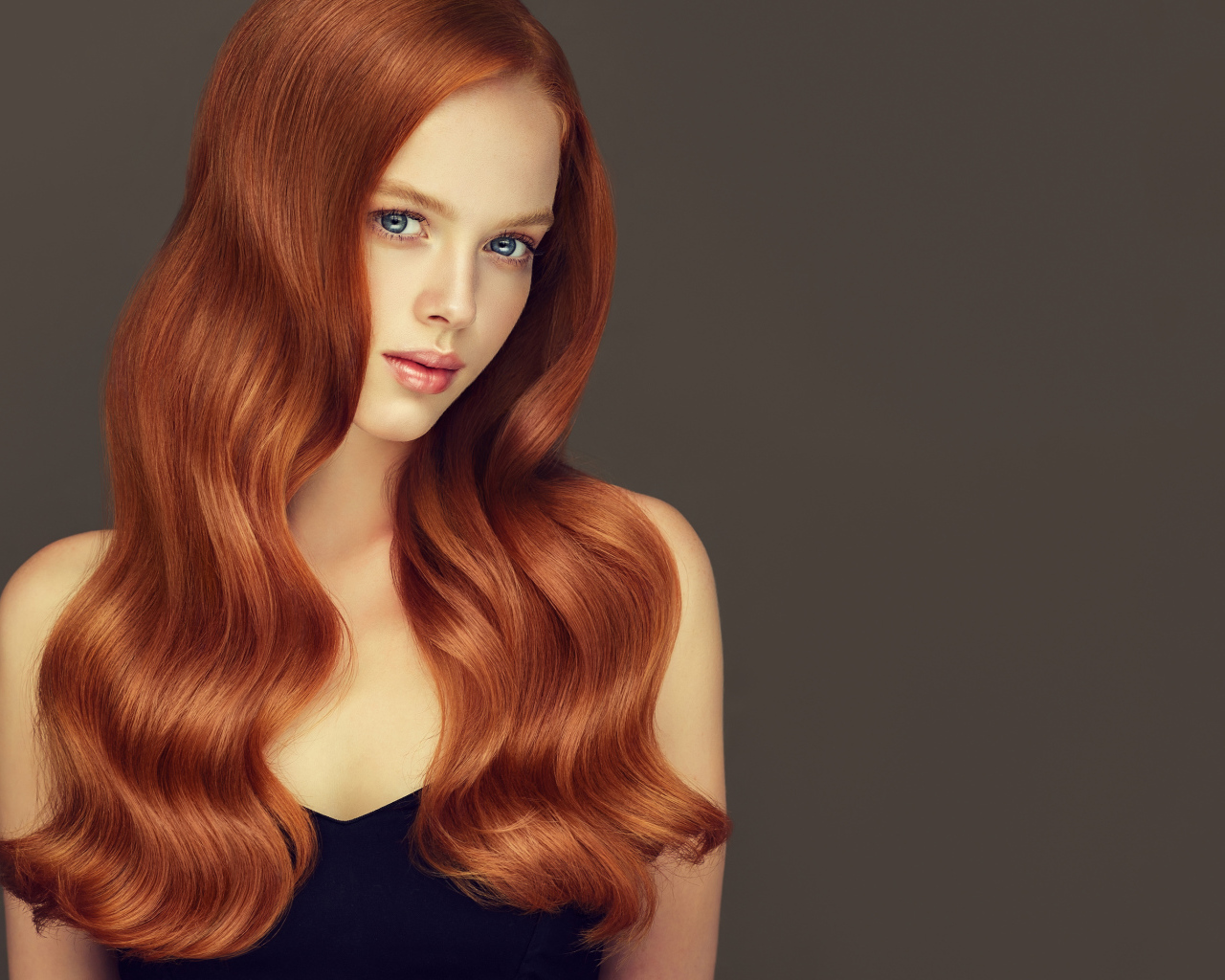 Красивая рыжеволосая голубоглазая девушка на сером фоне