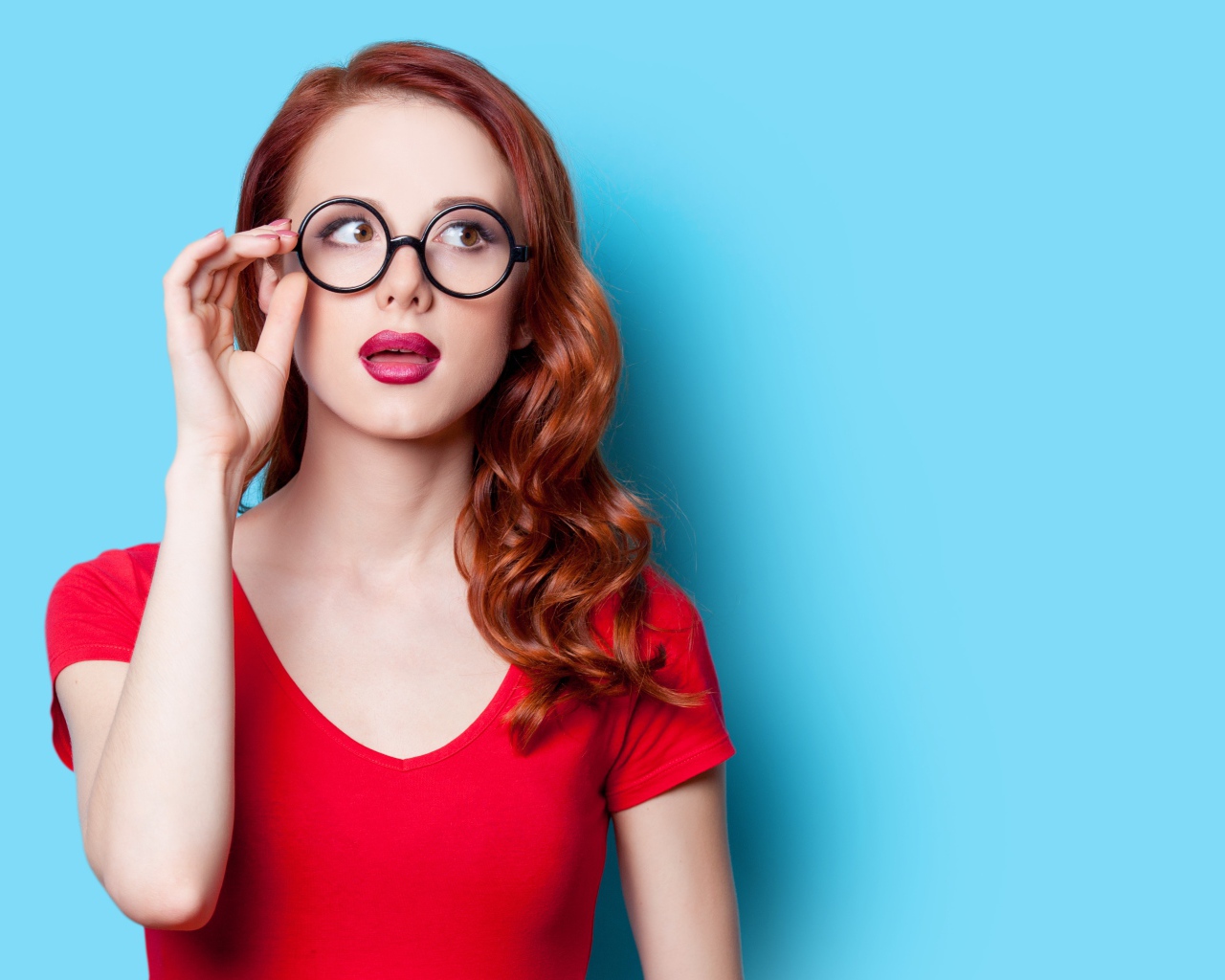 Красивая рыжеволосая девушка в очках на голубом фоне