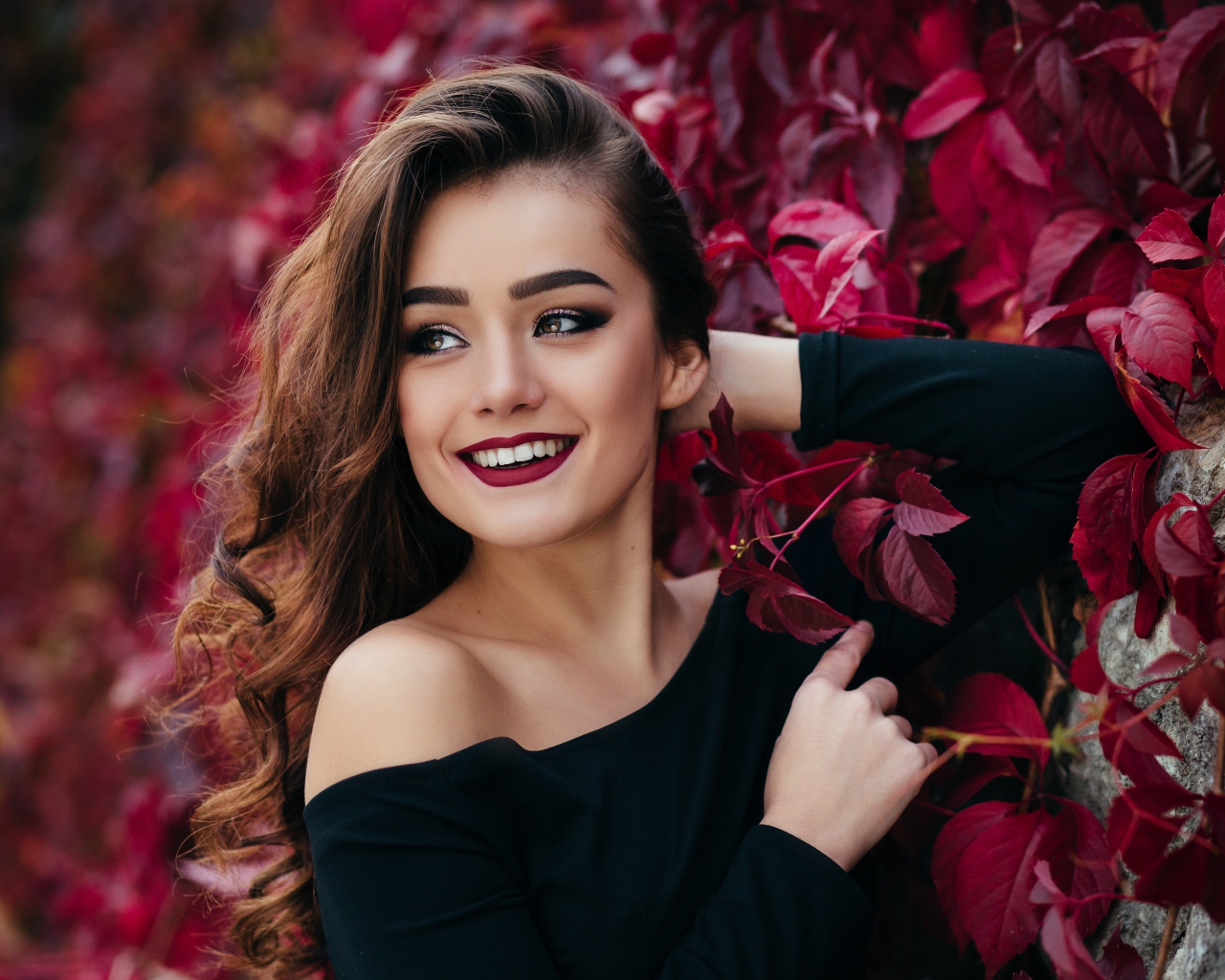 Красивая улыбающаяся длинноволосая девушка у стены с декоративным виноградом