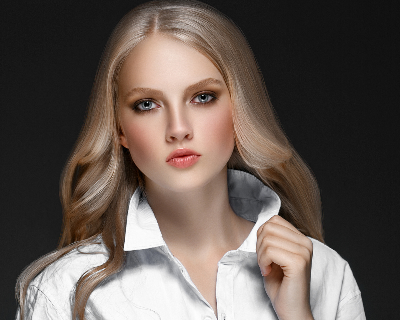 Красивая стильная голубоглазая блондинка в белой рубашке на сером фоне