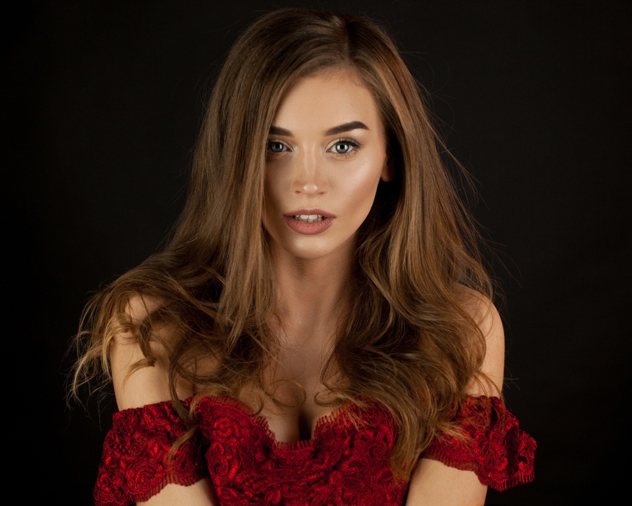 Красивая нежная длинноволосая шатенка в красном платье на черном фоне