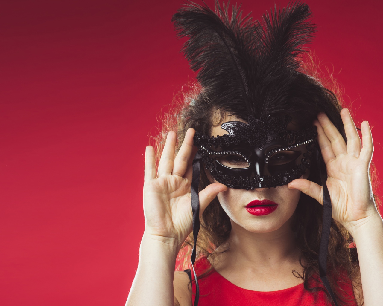 Красивая женщина в черной маске на красном фоне