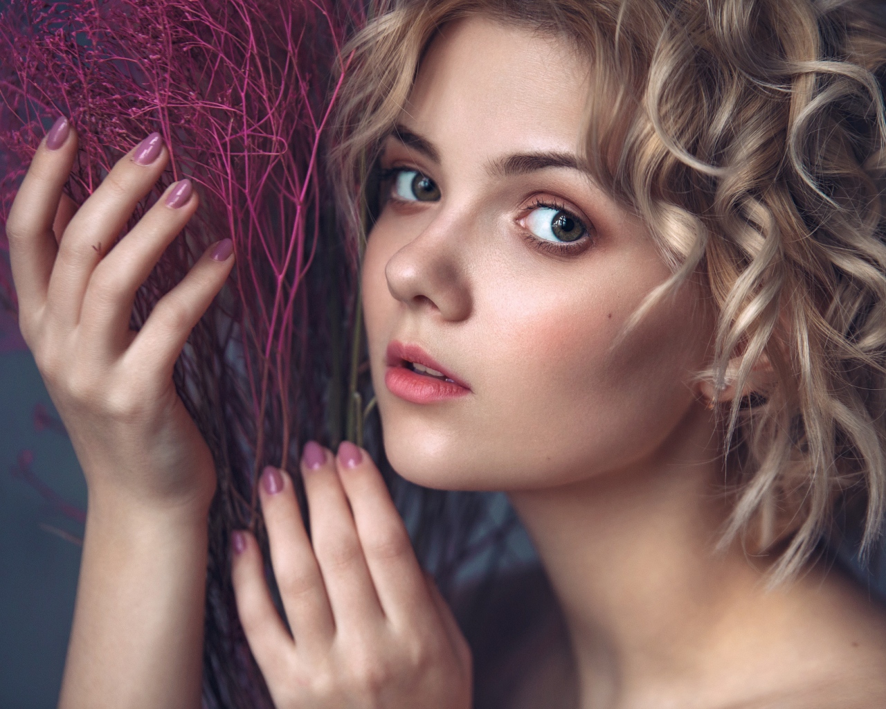 Красивая молодая блондинка с красным растением в руках