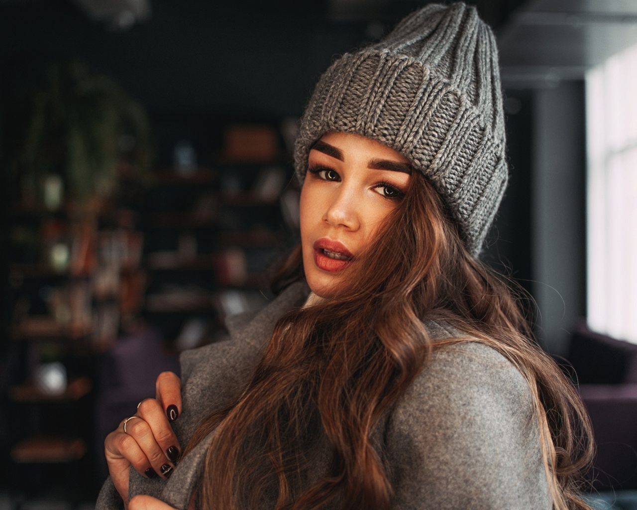 Красивая молодая девушка в пальто в вязаной шапке