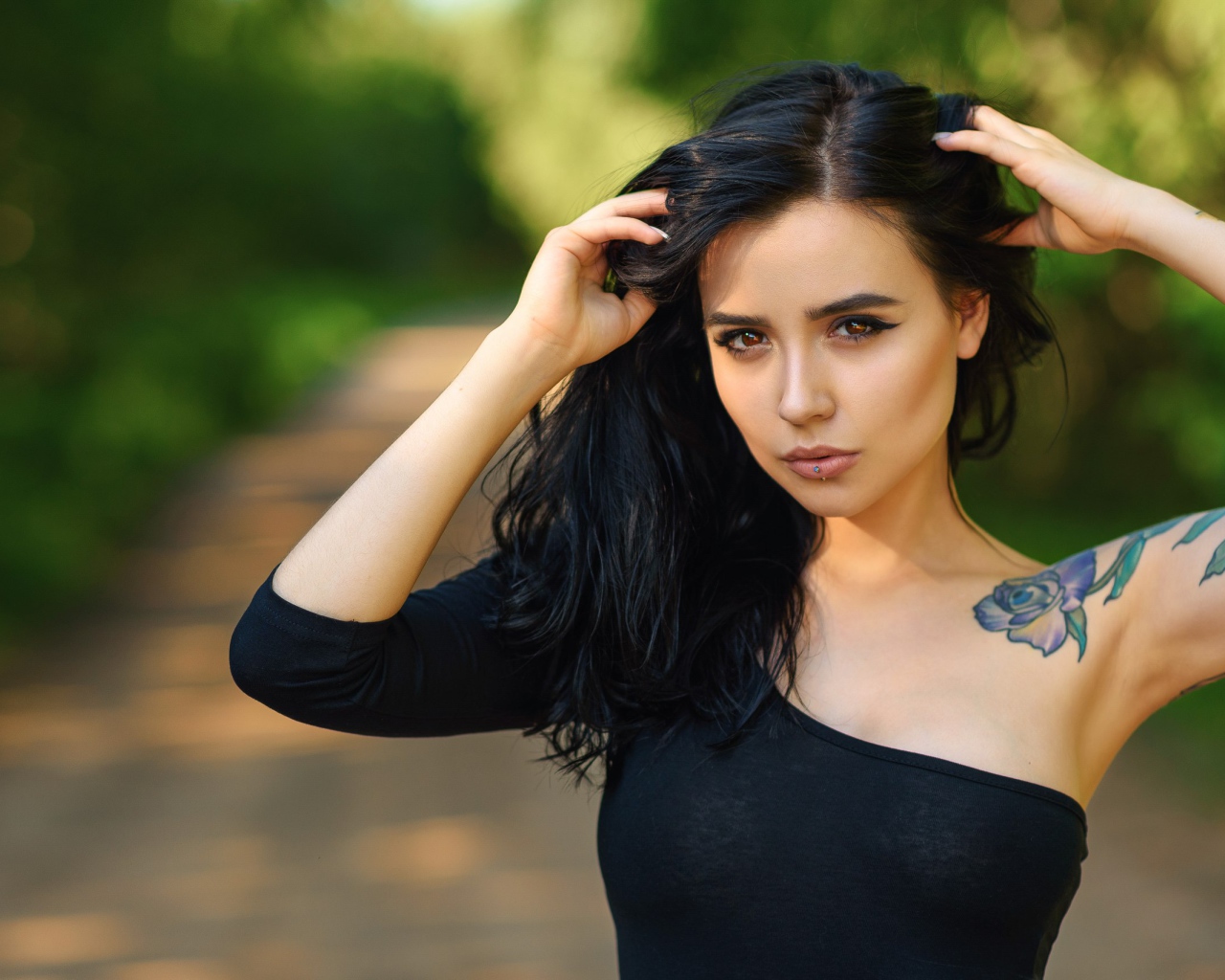 Красивая молодая девушка в черном с татуировкой на руке
