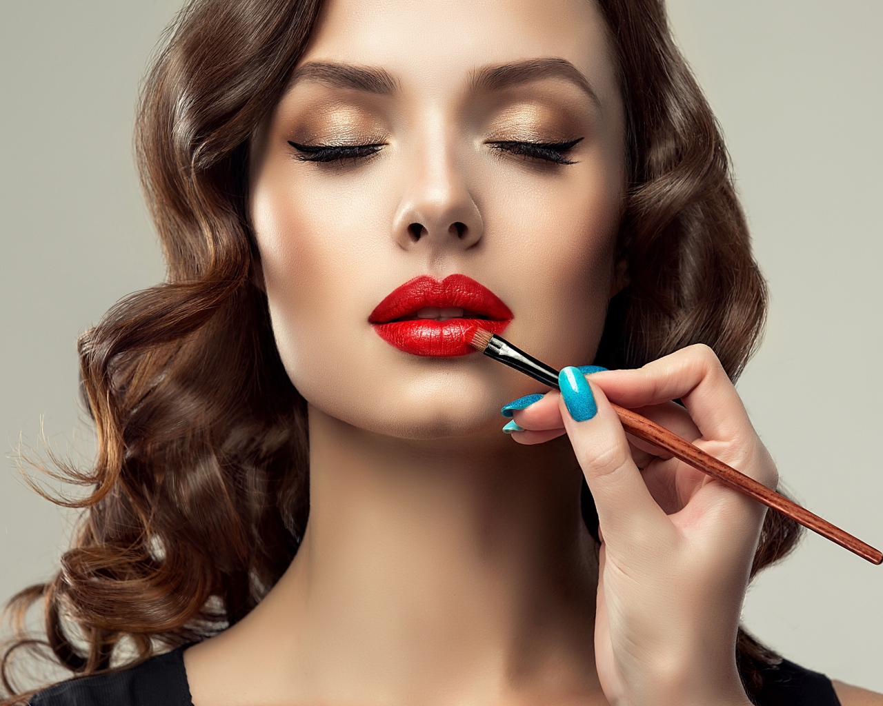 Красивой молодой девушке с закрытыми глазами делают макияж 