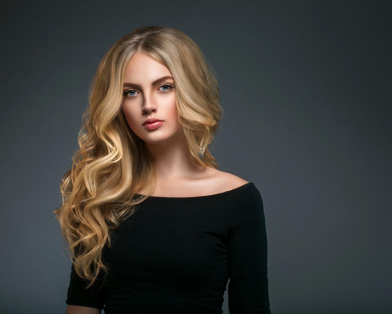 Красивая молодая девушка с длинными волосами в черном наряде на сером фоне