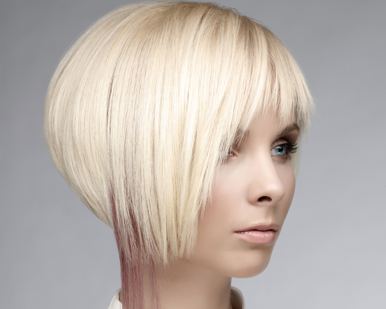 Голубоглазая девушка блондинка с короткой стрижкой на сером фоне