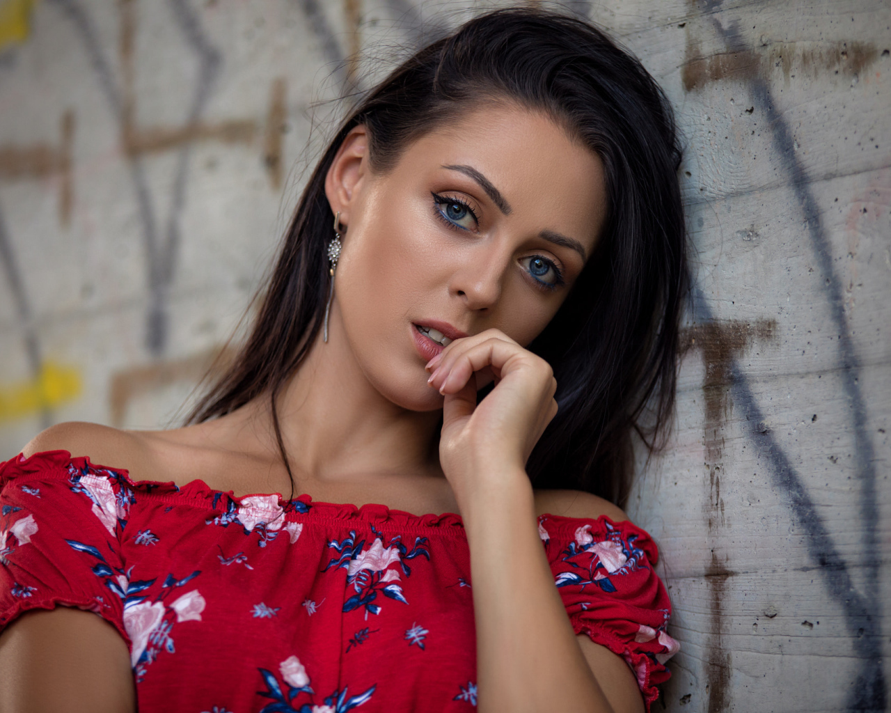 Голубоглазая брюнетка стоит в платье стоит стены